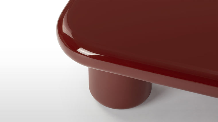 Deep Glossy Color | The table is crafted with a glossy lacquer finish in a deep burgundy color. Its sturdy construction includes rounded edges and round column legs.
