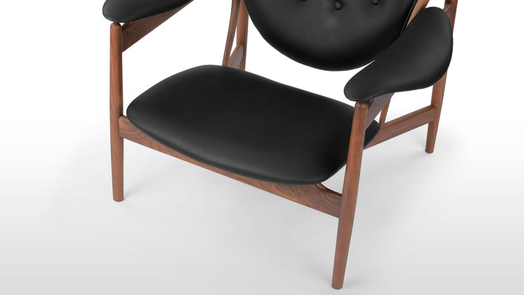 Rich Harmony | Combining the warmth of walnut with the sophistication of black leather in a vegan option, the chair boasts a luxurious, sustainable blend. The four-buttoned backrest adds an artistic flourish to its refined design.
