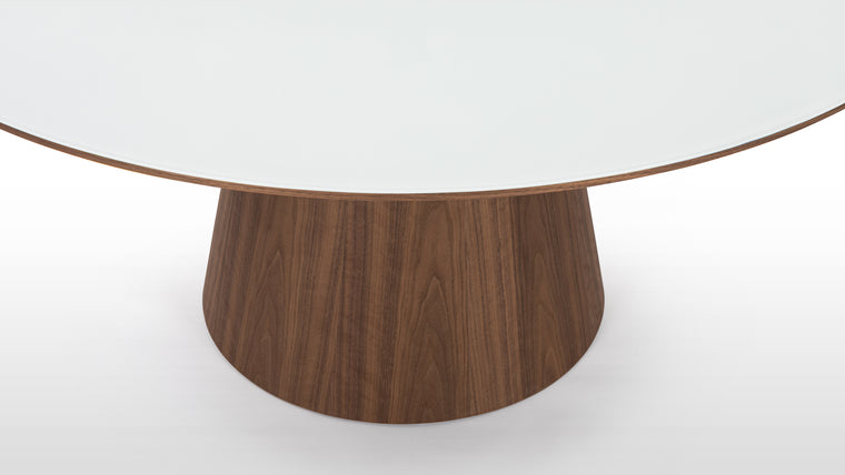 Contrasting Materials | Crafted with a choice of ceramic or white translucent glass for the tabletop, paired with a rich walnut base, the Cella Dining Table showcases a striking contrast between the sleek surface and the natural wood grain, adding warmth and texture to its refined form.
